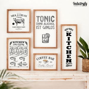 May include: Five framed signs with black and white illustrations and text. The signs are hung on a white wall. The signs read "The Old Milk & Cream Company", "Kitchen Conversions", "Tonic Ohne Alkohol Ist Ginlos", "Coffee Bar Since 1926 Freshly Brewed", and "Self Serve Kitchen Always Open".
