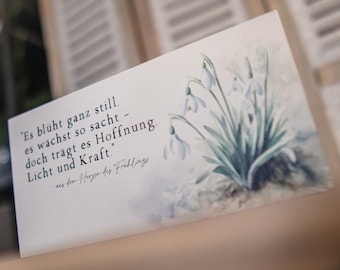 May include: A rectangular card featuring a watercolor illustration of snowdrop flowers with green leaves. The card has German text in a script font, including the phrase "Es blüht ganz still." The Industryfly logo is in the upper right corner.