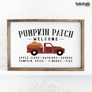 Könnte beinhalten: Ein weißes Schild mit braunem Holzrahmen, auf dem ein roter Lastwagen mit Kürbissen zu sehen ist. Das Schild lautet "Pumpkin Patch - Welcome - Apple Cider - Hayrides - Gourds - Pumpkin Spice - S'mores - Pies".