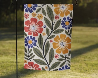 May include: A colorful garden flag with a floral pattern featuring red, yellow, blue, and green flowers on a white background.
