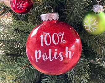 Op de afbeelding: Rode glitter kerstbal met witte tekst "100% polish".