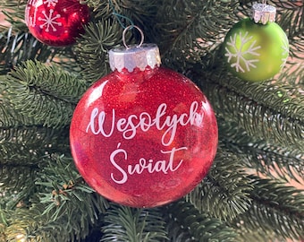Op de afbeelding: Een rode kerstbal met glitter en de tekst "Wesołych Świąt" in witte letters.