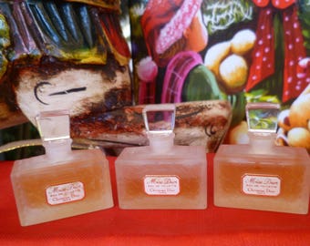 May include: Three clear glass bottles of perfume with frosted glass stoppers. The bottles are labeled "Miss Dior" and "Christian Dior".