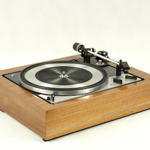 May include: A vintage wooden turntable with a black and silver platter and a tonearm. The turntable is in good condition and has a classic design.