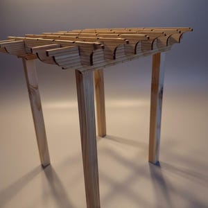 May include: A small wooden structure featuring four vertical legs supporting a horizontal roof section composed of parallel slats with curved, decorative ends. The light-colored wood displays a natural grain pattern throughout the entire assembly.