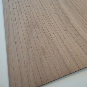 May include: A close-up of a light brown wood floor with a natural wood grain pattern. The floor is made of narrow planks that are arranged in a horizontal pattern.