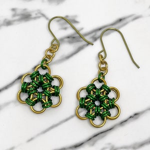 Könnte beinhalten: Ein Paar goldene und grüne Ohrringe mit einem Blumenmuster. Die Ohrringe sind aus Draht gefertigt und haben einen einfachen Hakenverschluss.