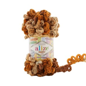 Könnte beinhalten: Eine Kugel braunen und beigen Garns mit schwarzen Flecken. Das Garn ist mit "Alize Puffy Color" gekennzeichnet und ist ein Garn ohne Nadeln oder Haken.