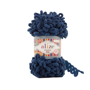 Op de afbeelding: Een bol blauwe Alize Puffy Fine garen. Het garen is zacht en snel te verwerken. Het etiket zegt "Soft & Quick" en "Alize Puffy Fine".