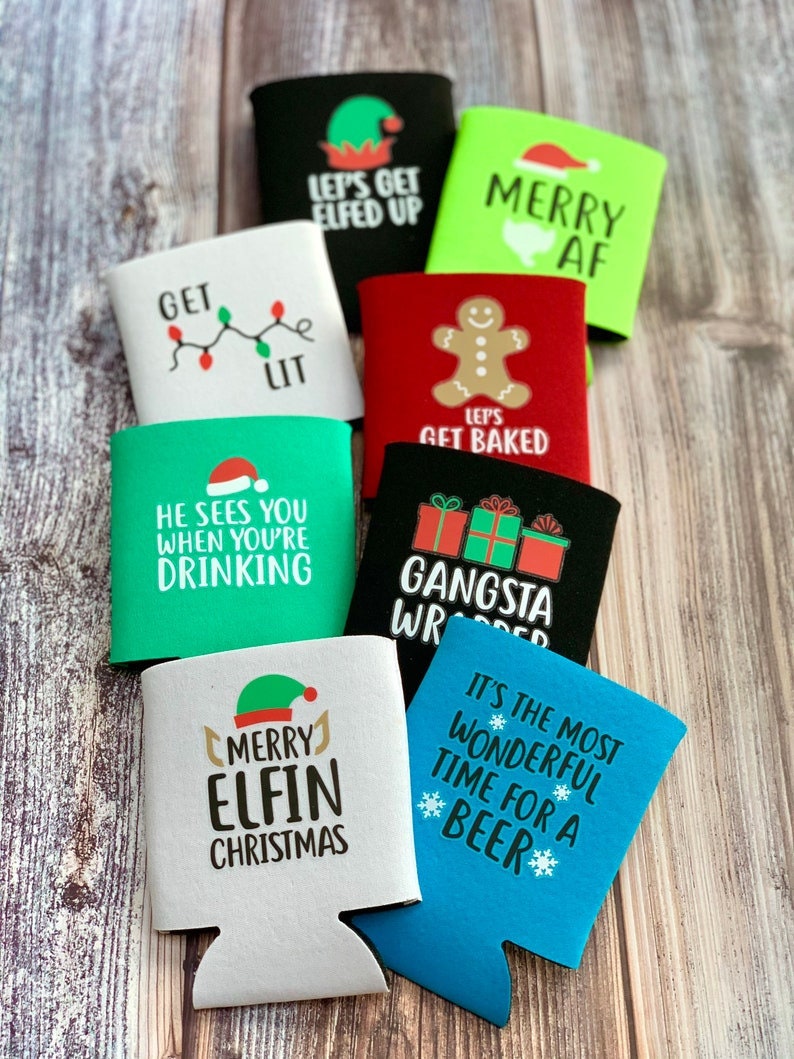 May include: A collection of ten Christmas-themed beverage insulators with various designs and sayings. The designs include a gingerbread man, a Christmas elf, a Christmas tree, and a Santa hat. The sayings include "Let's Get Elfed Up", "Merry AF", "Get Lit", "He Sees You When You're Drinking", "Let's Get Baked", "Gangsta Wrapper", "Merry Elfin Christmas", and "It's the Most Wonderful Time for a Beer".