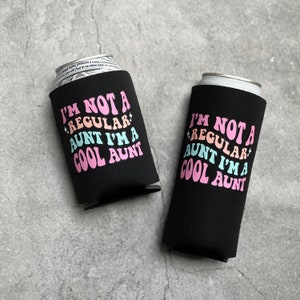 May include: Two black neoprene can coolers with pink, blue, and white text that reads "I'm not a regular aunt I'm a cool aunt".