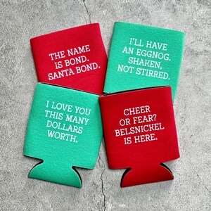May include: Four red and green can coolers with holiday-themed text. The text on the coolers reads: "The name is Bond. Santa Bond.", "I love you this many dollars worth.", "I'll have an eggnog. Shaken, not stirred.", and "Cheer or fear? Belsnickel is here."