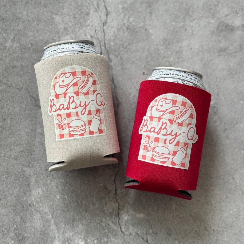 May include: Two can coolers, one tan and one red, each with a "Baby-Q" design. The design includes a cowboy hat, hot dog, burger, baby bottle, and a pacifier, all on a red and white checkered background. The coolers are designed to hold a standard-sized can.