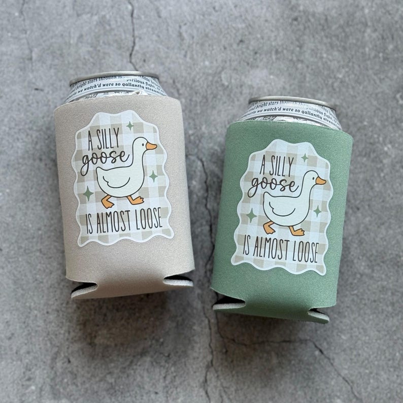 Op de afbeelding: Twee drankblikjeskoelers, &eacute;&eacute;n beige en &eacute;&eacute;n groen, elk met een wit etiket met een ganzenillustratie en de tekst "A SILLY goose IS ALMOST LOOSE". De koelers zijn ontworpen om drankjes koud te houden.