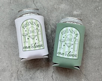May include: Two green and white insulated beverage holders with the text "Bikinis & Martinis" printed on them. The holders are designed to fit a standard can or bottle.