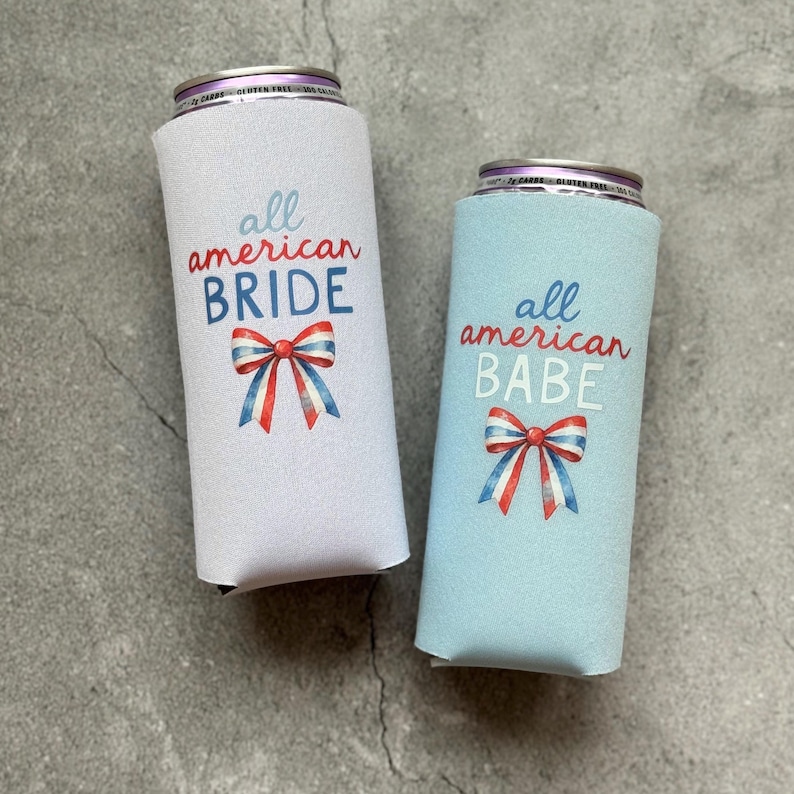 May include: Two slim can coolers, one white and one light blue. The white cooler reads "all american BRIDE" and the blue cooler reads "all american BABE" in red and blue text. Each cooler features a watercolor bow in red, white, and blue.