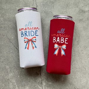 May include: Two can coolers, one white and one red, with patriotic designs. The white cooler says "all american BRIDE" and the red cooler says "all american BABE". Both have a bow in red, white, and blue.