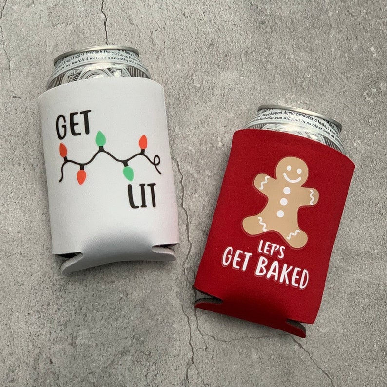 May include: Two white and red insulated beverage holders. The white holder has a string of Christmas lights with the text "Get Lit". The red holder has a gingerbread man with the text "Let's Get Baked".
