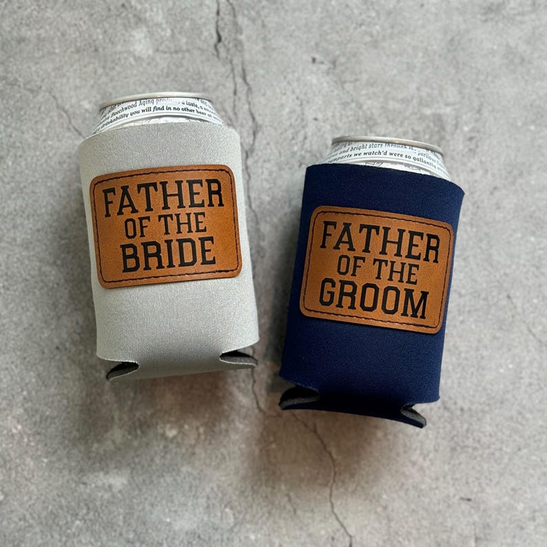 May include: Two can coolers, one light gray and one navy blue, each with a brown leatherette patch. The light gray cooler reads "FATHER OF THE BRIDE" and the navy blue cooler reads "FATHER OF THE GROOM".