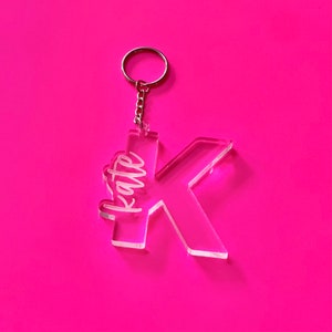 May include: A clear acrylic keychain with the letter K and the name "Kate" engraved on it.