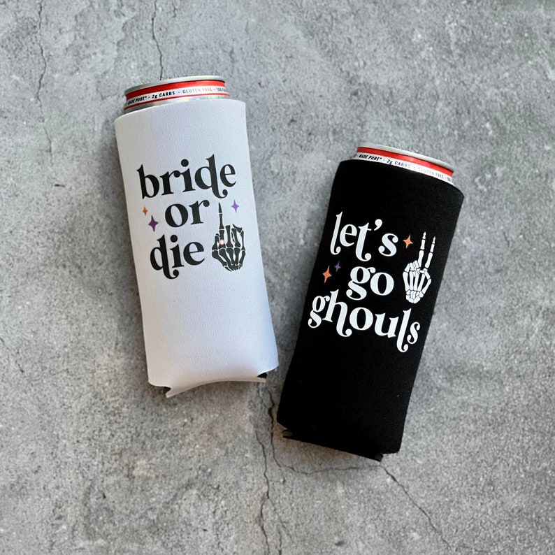 May include: Two black and white can coolers. One cooler says "bride or die" with a skeleton hand giving the middle finger. The other cooler says "let's go ghouls" with a skeleton hand giving the peace sign.