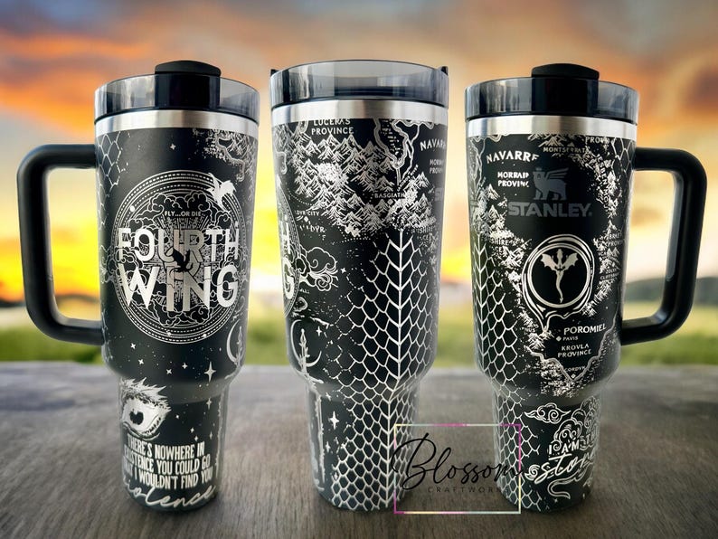 May include: Three stainless steel tumblers with black and silver designs. The tumblers feature a map of a fictional land with the words "Fourth Wing" on one, "Luceras Province" on another, and "Navarre, Morrasp Provinc, Stanley" on the third.