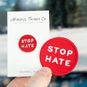 May include: A red enamel pin and a red patch with the words "STOP HATE" in white. The pin is round with a silver border, and the patch is embroidered. The pin is on a white card with the text "MINDFUL THINGS CO."
