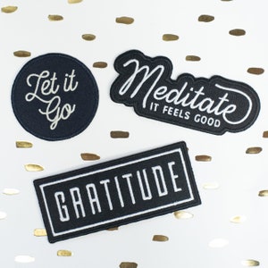 Könnte beinhalten: Drei schwarze gestickte Aufnäher mit weißen Buchstaben. Die Aufnäher sagen "Let it go", "Meditate It Feels Good" und "Gratitude".