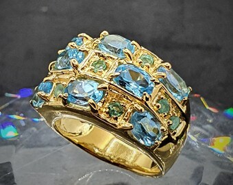 Puede incluir: Un anillo de oro con una banda de piedras ovaladas azules y verdes.