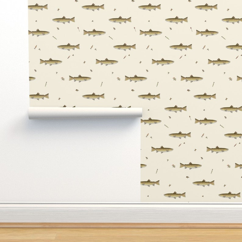 May include: Wallpaper roll featuring a repeating pattern of brown fish, arrows, and small insects on a cream background. The wallpaper is partially installed on a wall, with a roll visible at the bottom. The design has a rustic, outdoorsy feel.