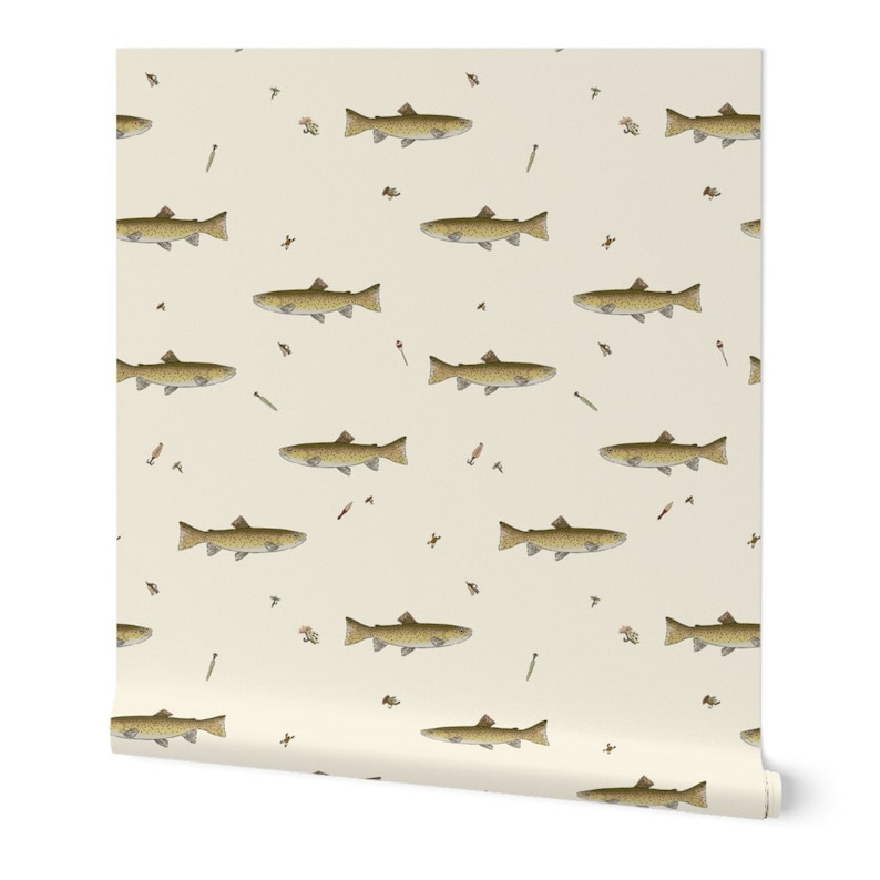 May include: A roll of wallpaper featuring a repeating pattern of brown fish with dark spots, fishing flies, and bobbers on a cream background. The wallpaper has a slight sheen and is rolled up, showing the pattern's edge. The design is suitable for a fishing or outdoors theme.