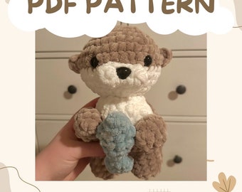 May include: Crochet pattern for a brown and white otter holding a blue fish. The pattern is available as a PDF download. PDF PATTERN.