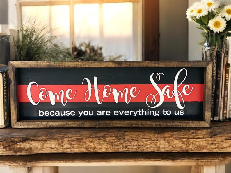 May include: A wooden sign with a red and black background. The sign says "Come Home Safe because you are everything to us".