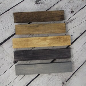 May include: Five wooden boards stained in different colors. The colors are dark brown, light brown, medium brown, dark gray, and light gray.