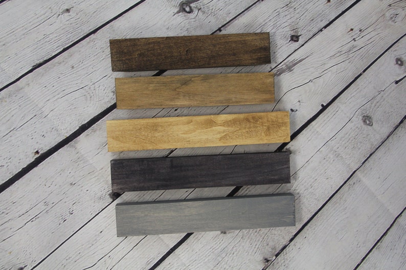 May include: Five wooden boards stained in different colors. The colors are dark brown, light brown, medium brown, dark gray, and light gray.
