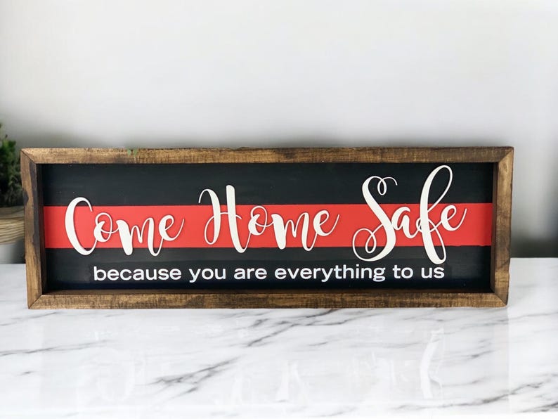 May include: A wooden sign with a red and black background. The sign says "Come Home Safe because you are everything to us".