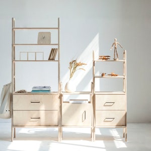 May include: A set of modular wooden shelves with drawers and open shelves. The shelves are made of light wood and have a simple, modern design. The shelves are arranged in a staggered pattern, creating a unique and interesting look.