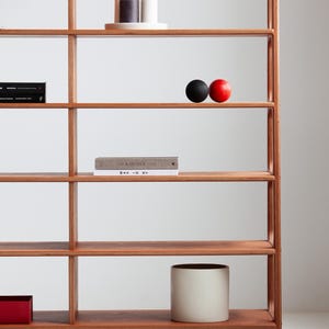 Minimalist mid century wooden ladder bookcase with seven empty shelves, showcasing the modular layout and slim side legs, handmade in a small workshop in Poland.