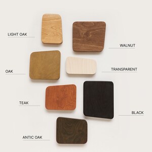 Op de afbeelding: Een staalkaart van hout afwerkingen in verschillende kleuren, waaronder licht eiken, walnoot, eiken, transparant, teak, zwart en antiek eiken. De houtstalen zijn gerangschikt in een rasterpatroon op een witte achtergrond. De tekst "SAMPLER 1" staat bovenaan de afbeelding.