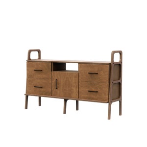 Op de afbeelding: Een houten kast in mid-century modern stijl met vier lades en een deur. De kast heeft een lichtbruine houtkleur en zwarte beslag.