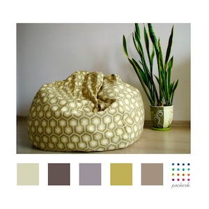 Può includere: Una poltrona sacco gialla e grigia con un design geometrico. La poltrona è seduta su un pavimento di legno con una pianta verde in un vaso marrone sullo sfondo.