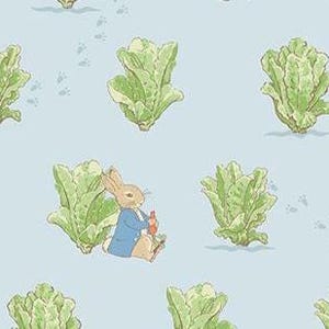 May include: A light blue fabric featuring a repeating pattern of green lettuce and a seated rabbit wearing a blue jacket, holding a carrot. Small gray paw prints are scattered across the background.