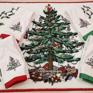 May include: Set of four white cotton hand towels with red and green trim. Each towel features an embroidered image of a Christmas tree with ornaments and presents. The towels are displayed on a white background with an embroidered Christmas tree design.