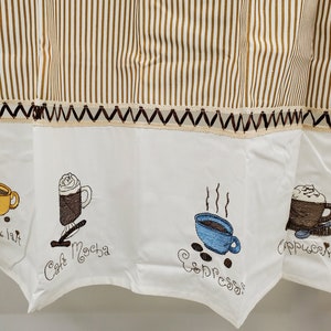May include: White kitchen valance with brown stripes and embroidered coffee cups. The valance features the words "Cafe au Lait", "Cafe Mocha", "Espresso", and "Cappuccino" in brown embroidery.