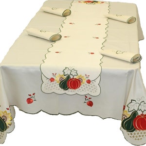 May include: A white tablecloth with a scalloped edge and embroidered pumpkins, leaves, and sunflowers. The tablecloth is paired with a matching runner and four napkins.