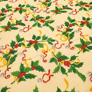 May include: Cream-colored fabric with a repeating Christmas pattern. The design features green holly leaves, red berries, yellow and red ribbons, and silver bells. A festive holiday theme.