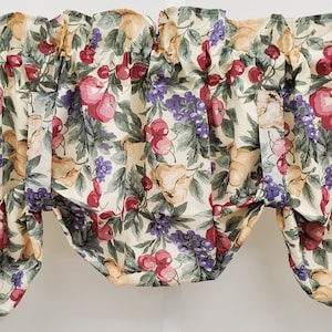 May include: A cream-colored valance with a fruit print featuring red apples, purple grapes, and green leaves.
