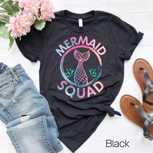May include: Black t-shirt with a mermaid tail graphic and the text "Mermaid Squad" in a rainbow watercolor style.