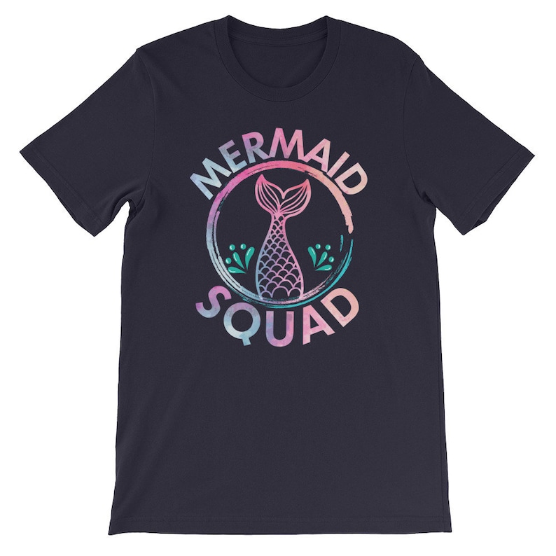 May include: A navy blue t-shirt with a pink, blue, and green watercolor design of a mermaid tail inside a circle with the text "Mermaid Squad".