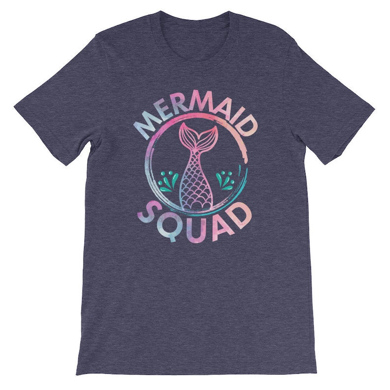 May include: A heather blue t-shirt with a pink, blue, and green watercolor design of a mermaid tail inside a circle with the text "Mermaid Squad".